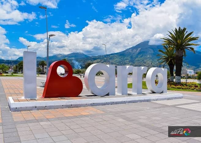 Letrero de Ibarra en una plaza, con montañas al fondo.