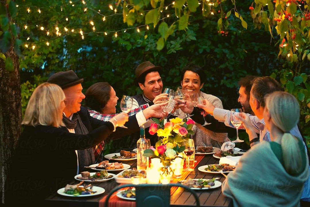 Grupo de personas adultas compartiendo una mesa al aire libre.